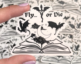 May include: Black and white sticker with an open book, a crescent moon, clouds, and three dragons. The text "Fly... or Die" is written above the book.