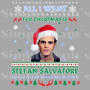 Puede incluir: Un suéter navideño gris con un gorro de Papá Noel rojo en la cabeza de un hombre. El suéter tiene un patrón verde y blanco con el texto "All I Want For Christmas Is Stefan Salvatore".