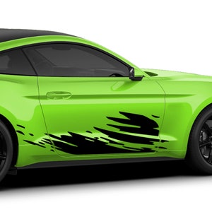 May include: A green car with black racing stripes on the side. The stripes are a stylized design of black brushstrokes.