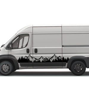 May include: A white van with a black mountain range decal on the side. The decal features a silhouette of mountains and trees.