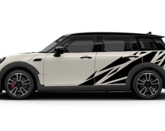 May include: A cream-colored Mini Cooper Clubman with black accents and a black roof. The car features black and white geometric decals on the side. The wheels are black with red brake calipers.