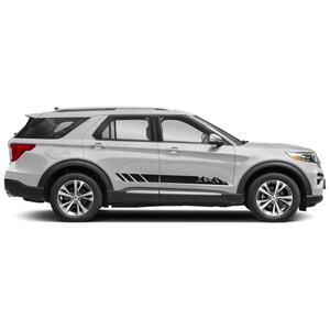 Puede incluir: Un SUV Ford Explorer blanco con calcomanías laterales negras que representan una cordillera montañosa. Las calcomanías están en la parte inferior de las puertas y se extienden hasta el paso de rueda trasero.