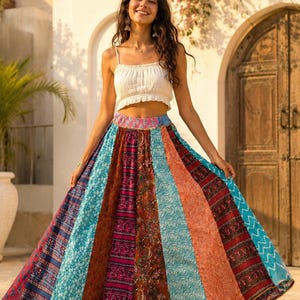 May include: A white sleeveless crop top with a gathered neckline paired with a floor-length, high-waisted skirt featuring vertical panels of multicolored fabric in shades of blue, orange, red, and purple with various intricate floral and geometric patterns.