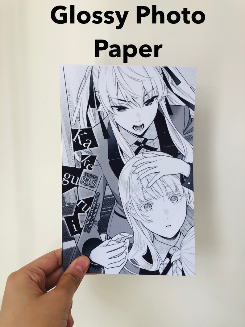 Peut inclure: Papier photo brillant avec une illustration de manga en noir et blanc. L'&oelig;uvre repr&eacute;sente deux personnages f&eacute;minins avec des expressions faciales et des coiffures d&eacute;taill&eacute;es. Le texte sur l'impression comprend "Kakegurui" et "Chapitre 83.5".