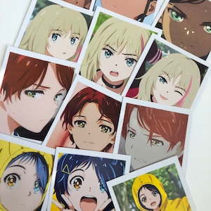 May include: A collection of anime character photo cards featuring various characters with different hair colors and eye colors. The characters are depicted in various poses and expressions.