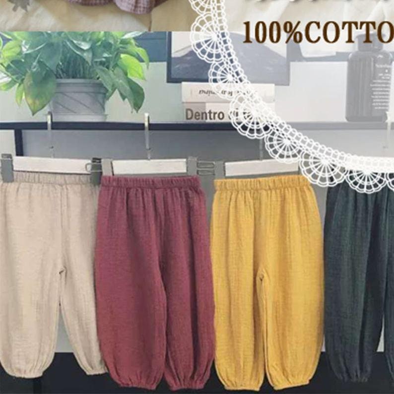 K&ouml;nnte beinhalten: Vier Paar Baumwollhosen h&auml;ngen an einem Gestell. Die Hosen sind in beige, burgunderrot, gelb und dunkelgr&uuml;n.