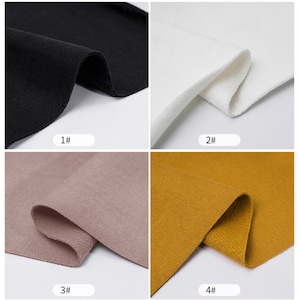May include: Four fabric swatches in different colors: black, white, light brown, and mustard yellow. The fabric is a soft, textured knit.