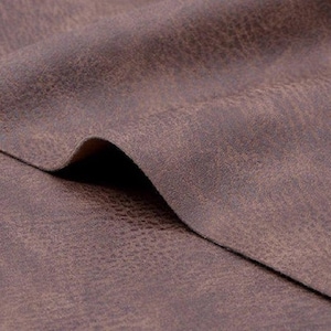 May include: Close-up of a brown faux leather fabric with a textured surface.