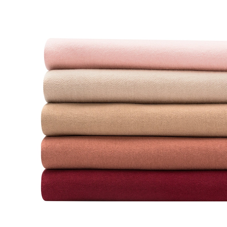 May include: A stack of five fabric swatches in various shades of pink, beige, brown, and red. The swatches are folded and arranged in a gradient from light to dark.