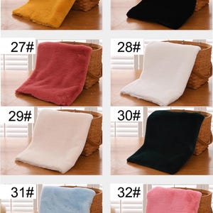 May include: Six different colors of faux fur fabric swatches displayed on a wooden table. The swatches are labeled with numbers 25 through 32.