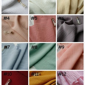 K&ouml;nnte beinhalten: Zw&ouml;lf Stoffmuster in verschiedenen Farben, darunter Wei&szlig;, Beige, Rosa, Rot, Blau, Gr&uuml;n und Grau. Der Stoff hat eine strukturierte, geknitterte Optik.
