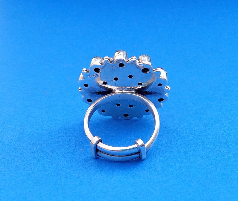 Puede incluir: Anillo de plata con un dise&ntilde;o floral y una banda de plata. El anillo est&aacute; engastado con peque&ntilde;as piedras redondas.