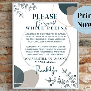May include: A white framed print with the text "PLEASE Be Seated WHILE PEEING". The print includes decorative leaf and abstract shapes in teal and beige. The text "Print Now!" is in a blue circle.