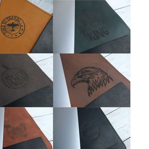 K&ouml;nnte beinhalten: Ein Set aus sechs verschiedenen Leder-Notizbuchh&uuml;llen mit verschiedenen Designs. Die Designs beinhalten ein Flugzeug mit dem Text "Time to Travel", einen K&uuml;rbis mit einem Gesicht, einen Adlerkopf, einen Schmetterling, einen Baseball und den Text "Born to be the King".