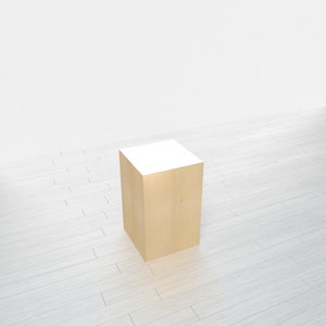 May include: A light wood square pedestal with a white top. The pedestal is sitting on a white wood floor.