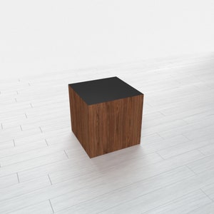 May include: A wooden cube with a black top. The cube is made of dark wood with a natural grain pattern.