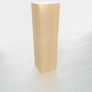 May include: A tall, rectangular wooden pedestal with a light brown finish. The pedestal is standing on a white wood floor.