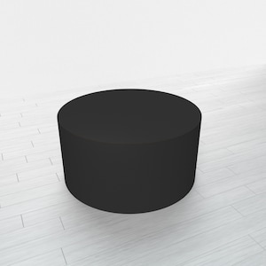 May include: A black round pedestal, or platform, made of a smooth material. It is sitting on a white wood floor.