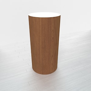 May include: A round wooden pedestal with a white top. The pedestal is made of light brown wood with a wood grain pattern.