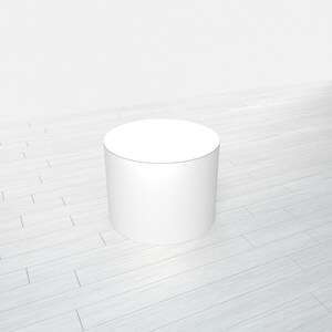 May include: A white cylindrical pedestal or platform, ideal for displaying products or showcasing items. The pedestal is on a light wood floor.