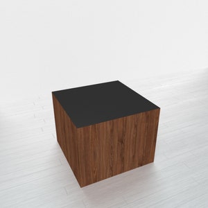 May include: A wooden cube with a black top. The cube is made of dark wood with a natural grain pattern.