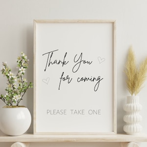 Puede incluir: Una impresión enmarcada en blanco con texto negro que dice "Thank You for coming" con dos pequeños corazones. Debajo del texto está "PLEASE TAKE ONE".