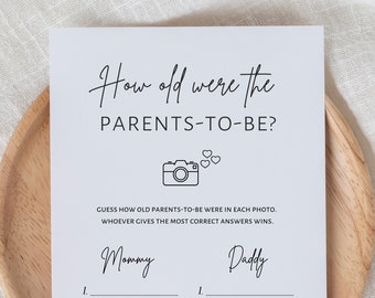 May include: A printable game card for a baby shower or bridal shower. The card has the text "How old were the PARENTS-TO-BE?" with a camera icon and hearts. The card has two sections for "Mommy" and "Daddy" with lines for writing in the answers.