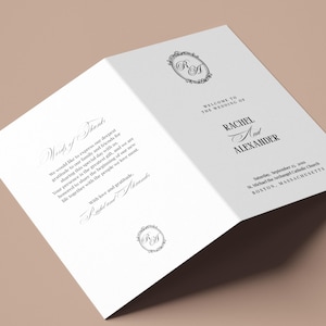 Puede incluir: Un programa de boda blanco plegado con una escritura elegante. El programa incluye los nombres "Rachel y Alexander" y la fecha de la boda. También hay adornos decorativos y un monograma.