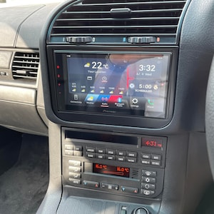 May include: A black car dashboard with a Pioneer touchscreen radio display showing the time, temperature, and other settings. The radio has a black and silver trim. Below the radio is a black control panel with buttons and a digital display showing the temperature in degrees Celsius.