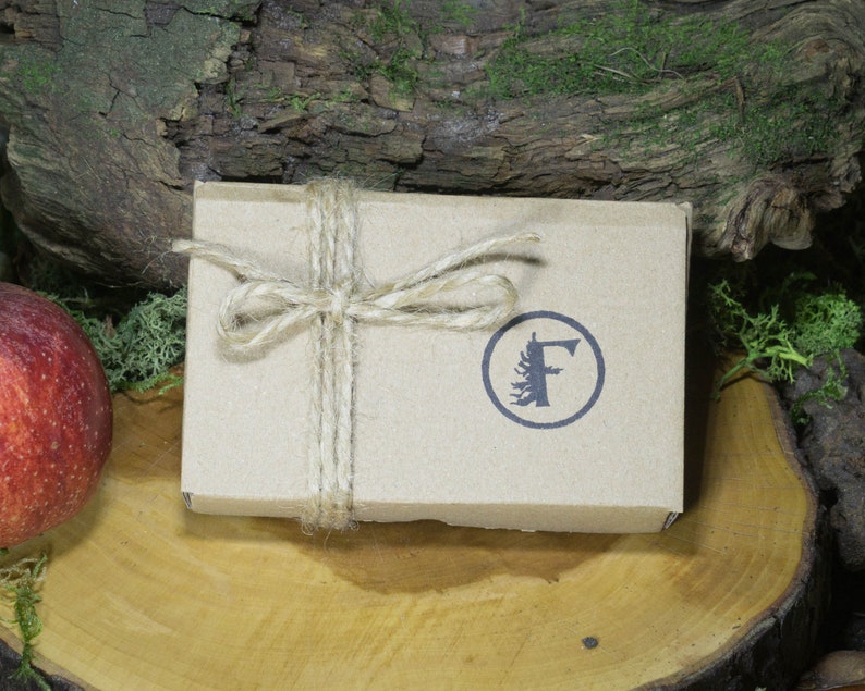 May include: A brown cardboard box tied with twine and a bow. The box has a logo with a stylized tree and the letter "F" in a circle.