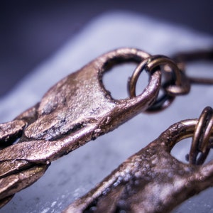 May include: Close-up of a pair of bronze earrings with a textured, braided design. The earrings have a unique, organic look and feel.