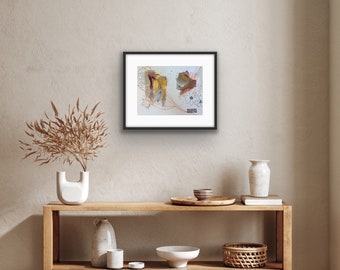 Puede incluir: Una impresión de arte abstracto enmarcada con un collage de formas y líneas coloridas. La impresión se coloca contra una pared beige claro, sobre un estante de madera con artículos decorativos.