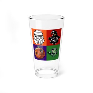 May include: A clear glass featuring a pop art design with four squares. The squares contain images of a Stormtrooper, Darth Vader, a pumpkin Death Star, and Yoda. The background colors are orange, red, purple, and green.