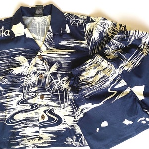 May include: A navy blue and white Hawaiian shirt and matching shorts set with a palm tree and river design. The shirt has a button-up front and short sleeves. The text "Ha" is embroidered on the left side of the shirt.