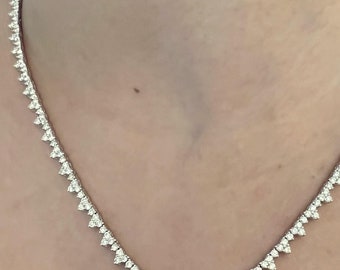 May include: A delicate, silver-toned necklace featuring a series of sparkling, triangular-shaped gemstones. The necklace is designed to sit gracefully around the neckline, reflecting light and adding a touch of elegance. The gemstones are evenly spaced.