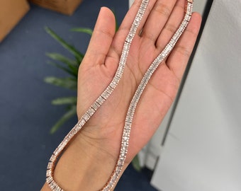 Op de afbeelding: Een roségouden ketting met een rij vierkante, heldere stenen.