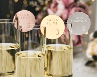Op de afbeelding: Drie heldere glazen champagneflutes, elk voorzien van een rond acryl naamplaatje aan de rand. De plaatjes zijn roségoud, goud en zilverkleurig, gegraveerd met de namen Keith Fox, Karen Flint en John Tompson, samen met het cijfer 3.