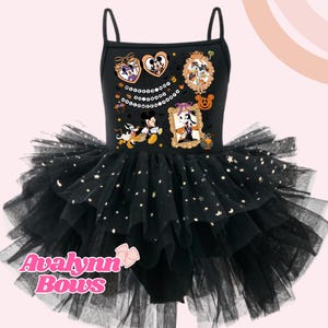 Può includere: Abito tutù nero a tema Halloween con corpetto con Topolino e Minnie, Paperino e Pippo in costume di Halloween. La gonna a tutù è a strati e decorata con accenti a forma di stella. Il marchio "Avalynn Bows" è visualizzato in basso.
