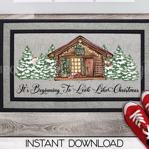 Puede incluir: Una alfombra de bienvenida gris con borde negro presenta una cabaña con luces, árboles cubiertos de nieve y el texto "It's Beginning To Look Like Christmas".