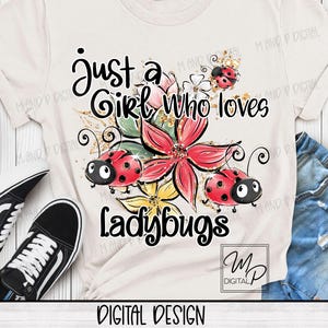 May include: Cream-colored t-shirt with the text "Just a Girl Who loves Ladybugs." The design features red ladybugs, pink and yellow flowers, and gold glitter accents. Black and white sneakers and denim shorts are visible.