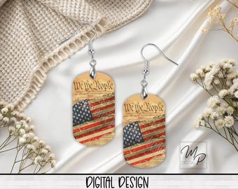 May include: A pair of silver earrings with a dog tag design. The dog tags feature a vintage-style American flag with the words "We the People" printed on the top.