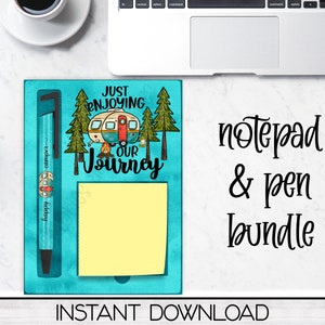 May include: A blue notepad and pen bundle with a camping theme. The notepad has a yellow sticky note and a design of a camper van, trees, and the text "Just Enjoying Our Journey".