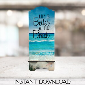 May include: A wooden sign with a blue and white beach scene and the text "Life is Better at the Beach".