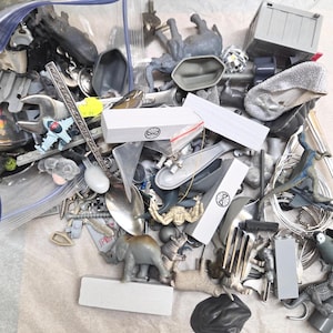 以下が含まれることがあります： おもちゃの動物、工具、ミニチュア容器など、さまざまな小さなオブジェクトのコレクション。アイテムは、グレー、シルバー、白など、さまざまな色があります。一部のアイテムは透明なビニール袋に入っています。