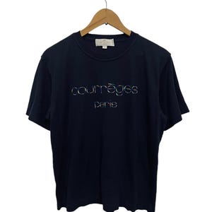 Op de afbeelding: Een marineblauw T-shirt met korte mouwen met een wit logo met de tekst "courr&egrave;ges paris" in een regenboogkleurig, iriserend lettertype.