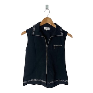 Puede incluir: Chaleco negro sin mangas con cremallera, cremallera plateada y logotipo plateado "ANIES VALENTINO ANIES" alrededor del cuello y el dobladillo inferior.