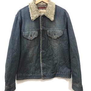 May include: A blue denim jacket with a striped pattern and a brown faux fur collar. The jacket has a button closure and two front pockets.
