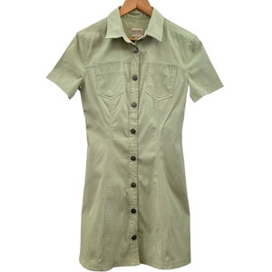 May include: A light green short-sleeved button-down dress with a collared neckline and two flap pockets. The dress has a label that reads "VERSACE Collection".