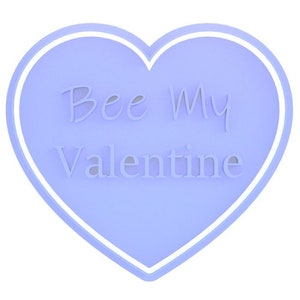 May include: A light purple heart-shaped decoration with the words "Bee My Valentine" in a cursive font. The heart has a white border and is set against a white background.