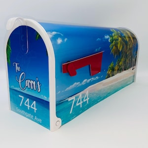 May include: A white mailbox with a tropical beach scene design. The mailbox has a red flag and the text "The Carri's 744 Southgate Ave" is printed on the front.